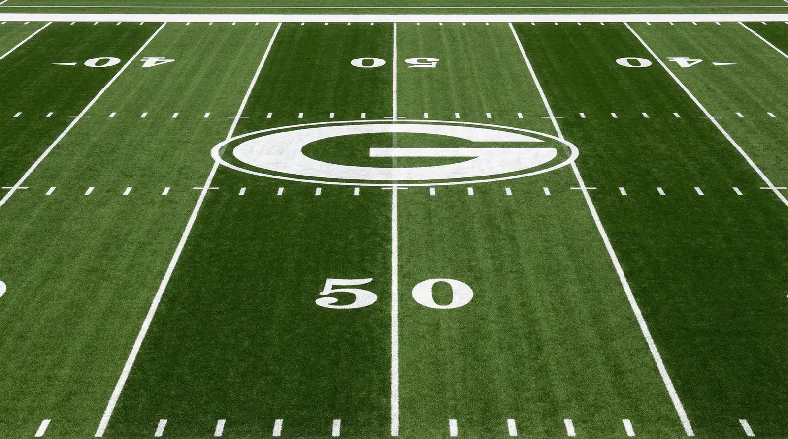 Vista cenital de un campo de fútbol americano con líneas de yardas bien marcadas